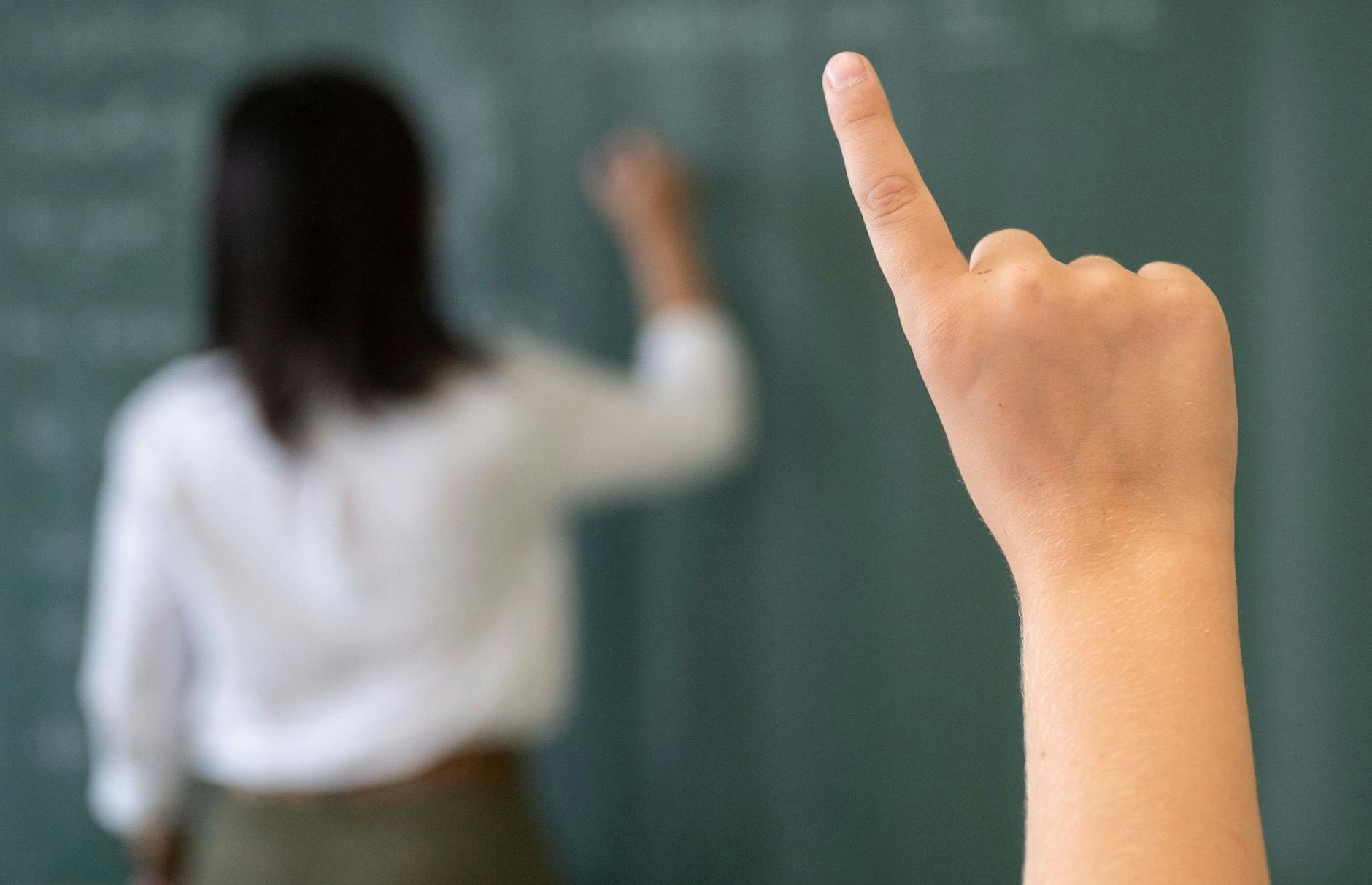 ARCHIV - Ein Schüler meldet sich, während die Lehrerin an die Tafel schreibt.