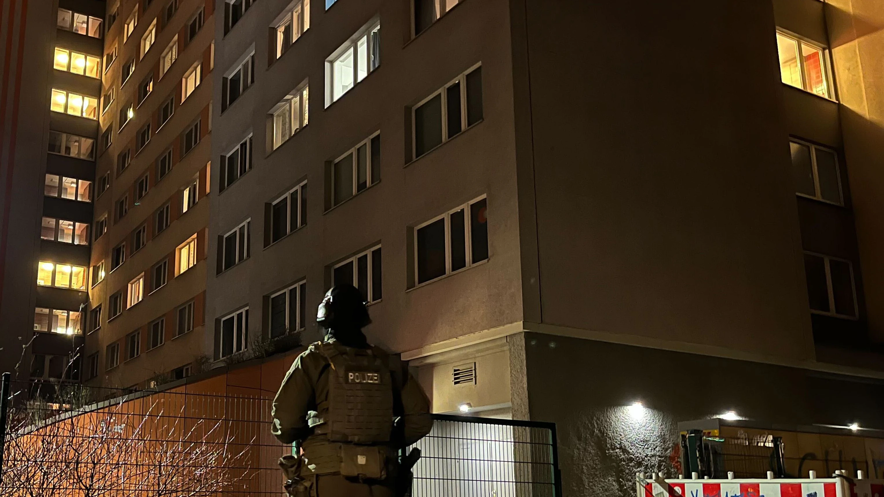 Ein schwer bewaffneter Polizist mit Helm sichert das Wohnheim an der Straße der Pariser Kommune&nbsp;in Berlin. Hier gab es am Dienstag weitere Durchsuchungen.