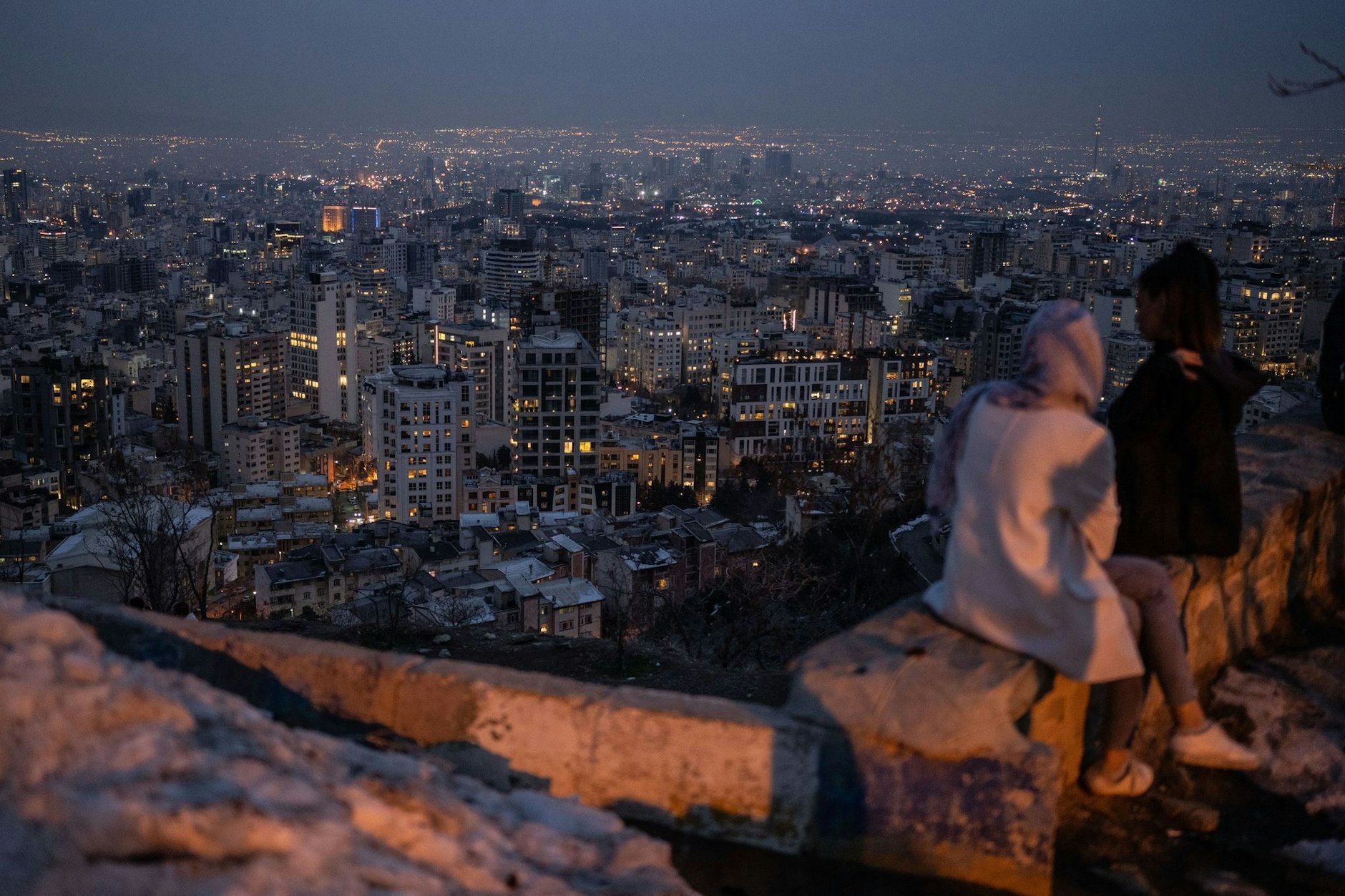 Zwei Frauen blicken nach Sonnenuntergang auf die Millionenmetropole Teheran.  