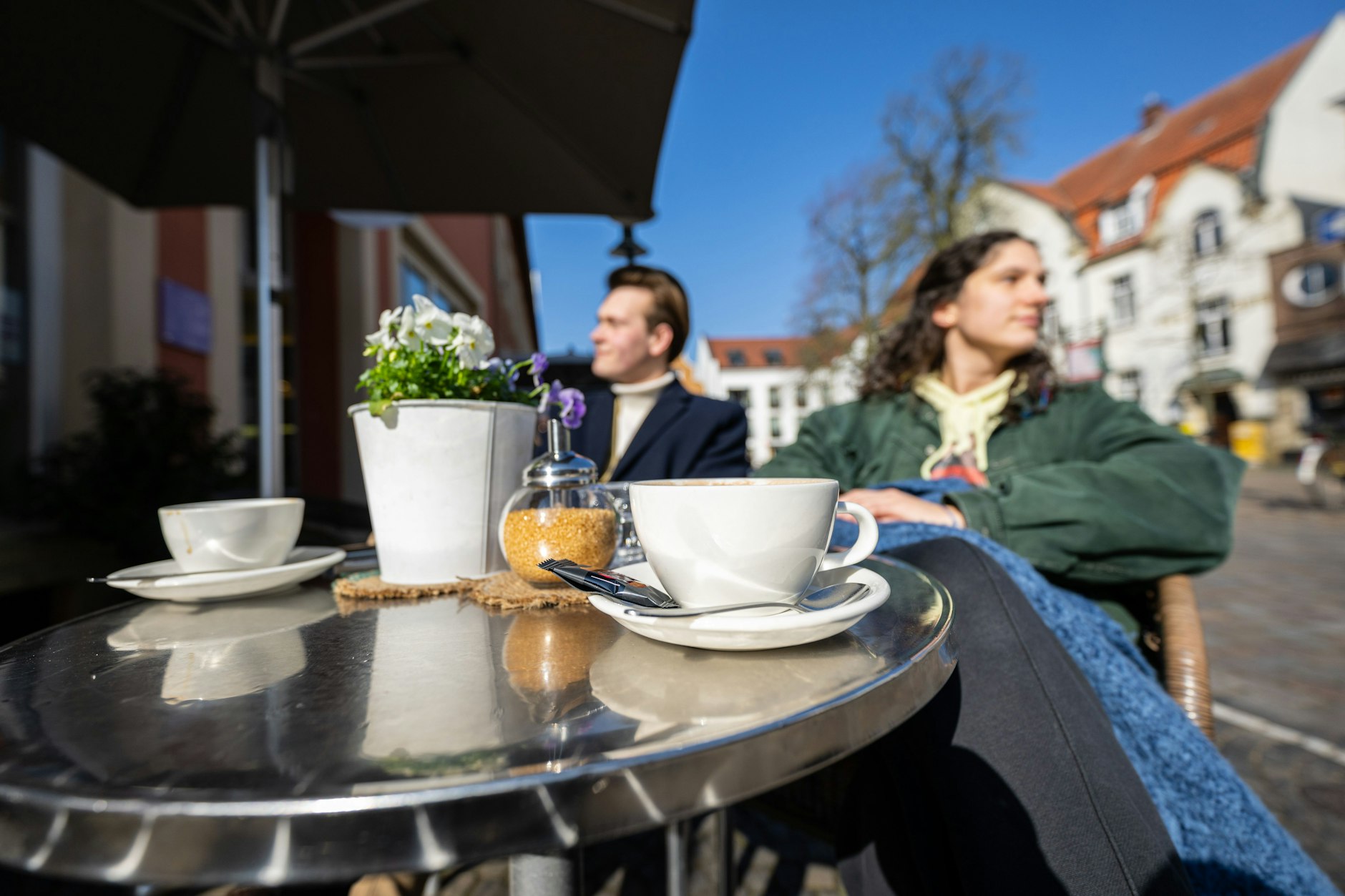 Ein junges Pärchen genießt bei Sonnenschein eine Tasse Kaffee im Café. Meteorologen sagen ein sonniges Wochenende voraus.