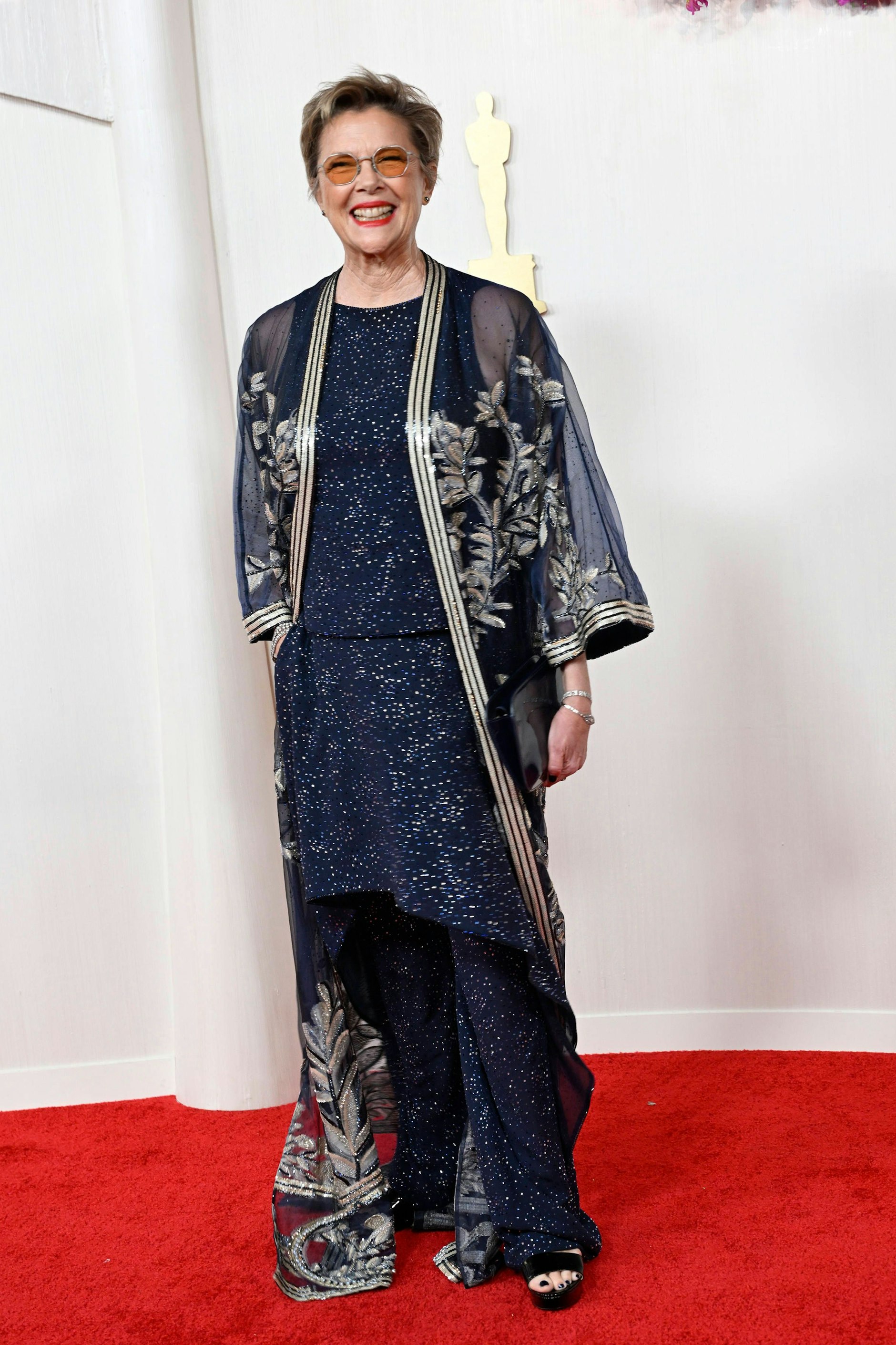 <strong>FLOP:</strong> Eigentlich sind die Textur und das Muster von <strong>Annette Benings</strong> Robe ein Treffer. Doch der kimonoartige Mantel über dem Kleid, das eine Hose verdeckt, verleiht dem Outfit etwas Unschlüssiges. Als wollte Bening für alle Möglichkeiten gewappnet sein: Party, Samurai-Schwertkampf, Gala und Abend auf der Couch. Schade, Gala hätte gereicht. 