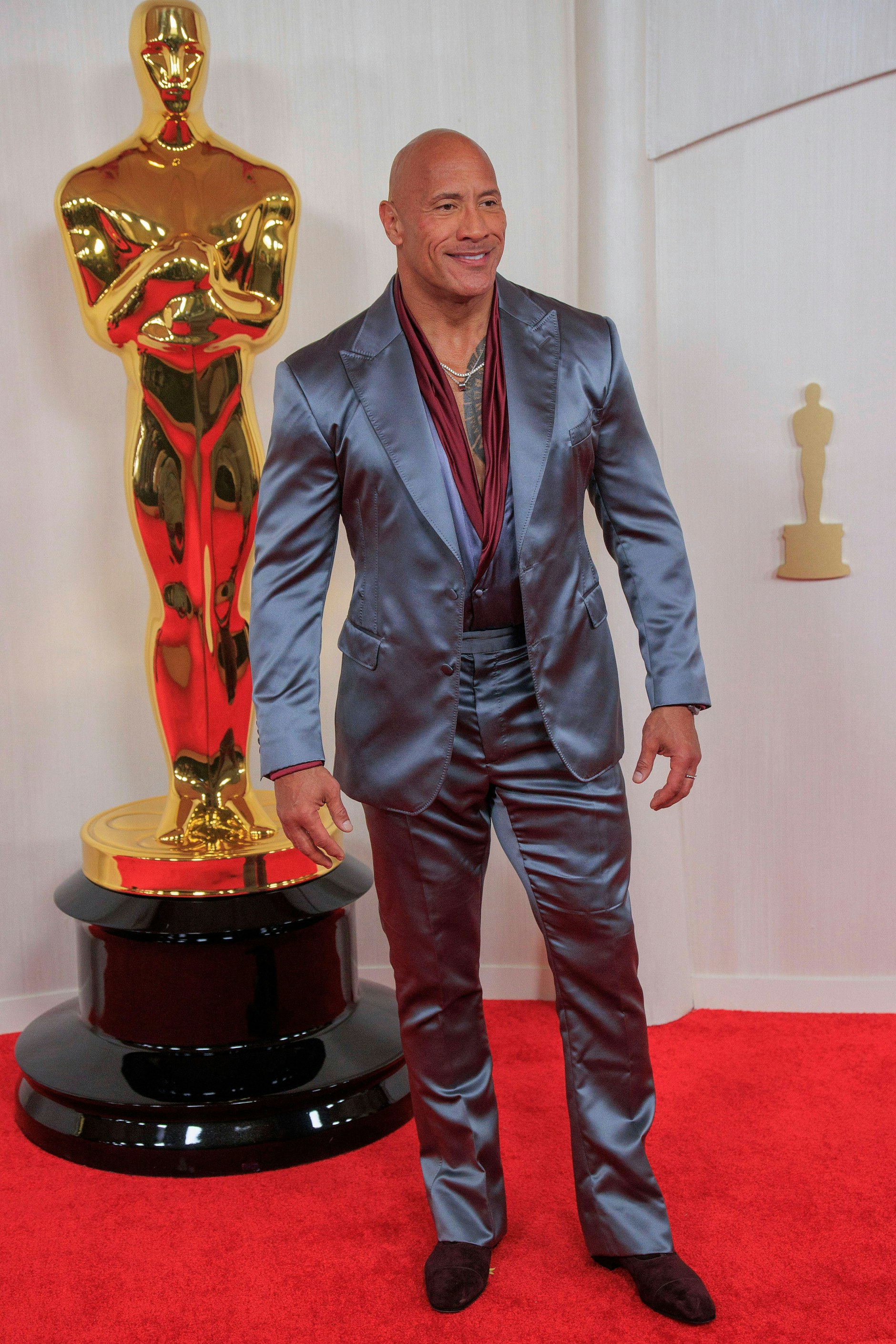 <strong>FLOP:</strong> Er&nbsp;gilt als einer der beliebtesten, weil grundsympathischen Hollywoodstars, was&nbsp;<strong>Dwayne Johnson</strong> bei seinem Anzug wohl helfen wird. Denn diese Mischung aus schimmernder Tagesdecke aus dem Stundenhotel, Türsteher-Outfit und Autolackierung ist ein kompletter Fehlgriff. Auch der bordeauxfarbene Satin-Schal darunter verhilft nicht zu mehr Seriosität und hat irgendwie was vom späten Elvis, der in Las Vegas immer seine Schwitztücher von der Bühne warf.