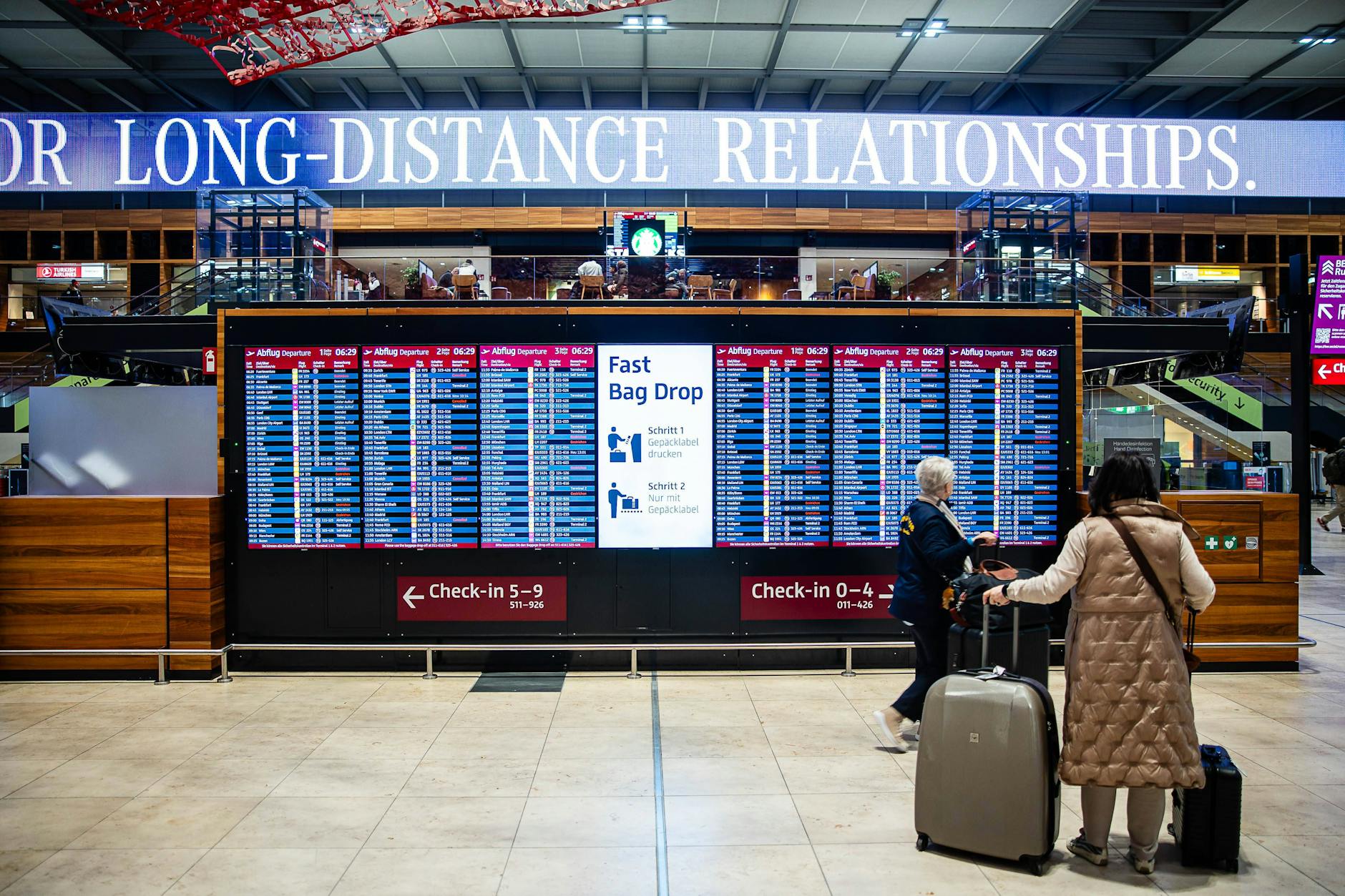 Reisende vor einer Anzeigetafel auf dem Flughafen BER