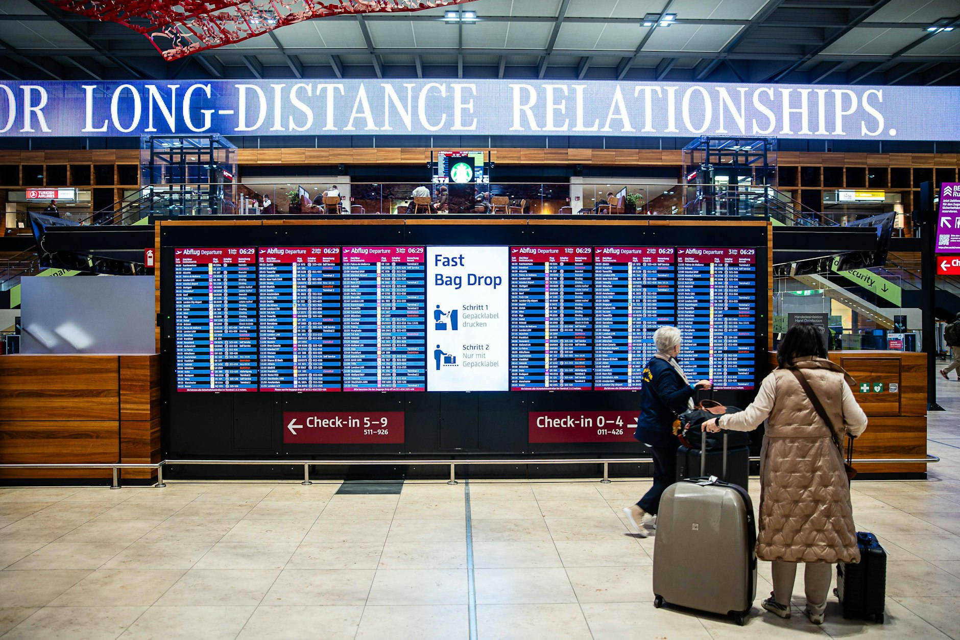 Reisende vor einer Anzeigetafel auf dem Flughafen BER