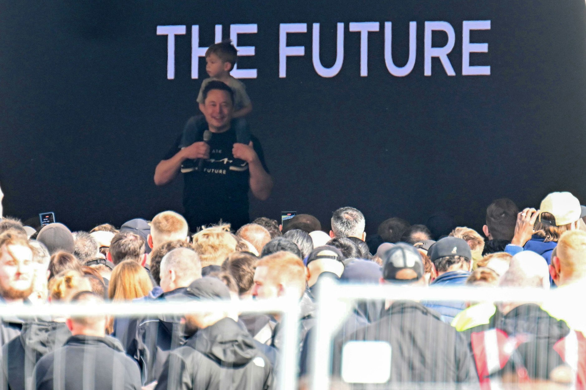 Tesla-Chef Elon Musk spricht in der Tesla-Gigafactory Berlin-Brandenburg zu den Mitarbeitern und trägt dabei ein Kind auf den Schultern. 