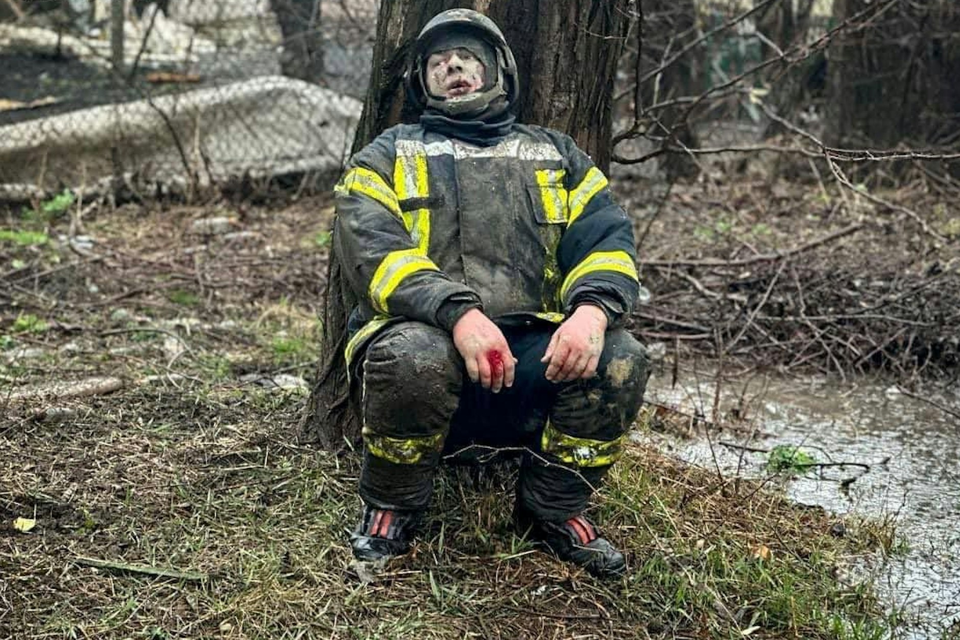 Ein geschockter Feuerwehrmann sitzt an einem Baum in der Nähe des Raketeneinschlagsortes in Odessa. Bei dem Angriff wurden auch Rettungskräfte getötet.
