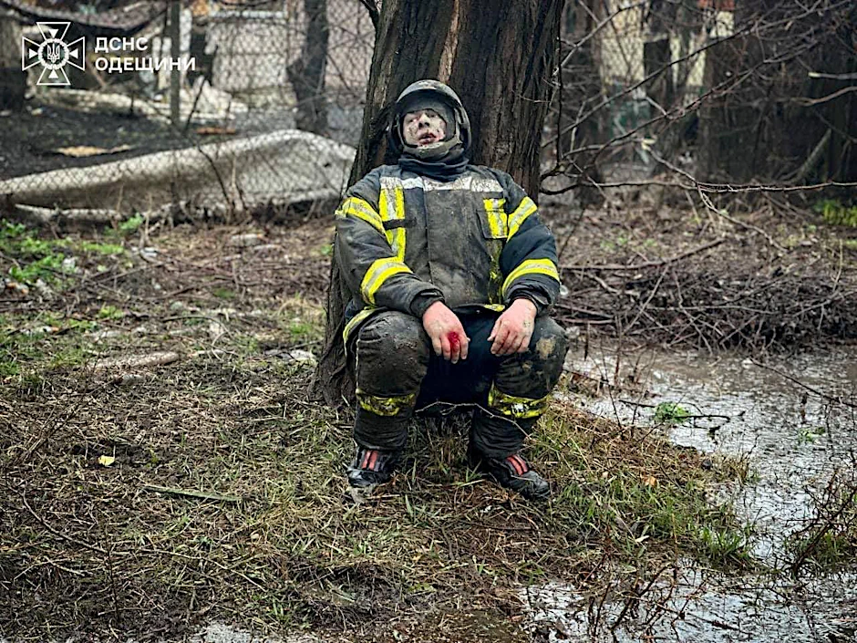 Ein geschockter Feuerwehrmann sitzt an einem Baum in der Nähe des Raketeneinschlagsortes in Odessa. Bei dem Angriff wurden auch Rettungskräfte getötet.