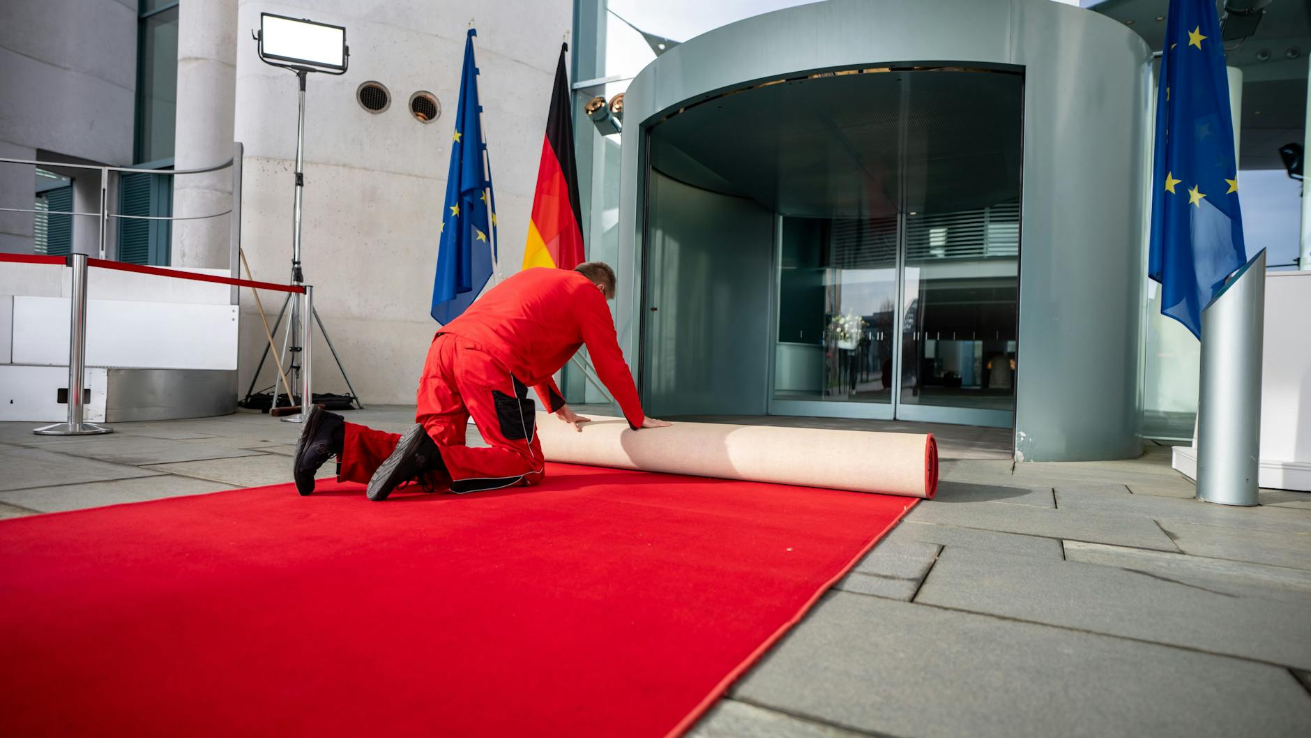 Ein Arbeiter rollt vor dem Treffen von Bundeskanzler Scholz mit Frankreichs Präsident Macron und Polens Regierungschef Tusk den roten Teppich vor dem Kanzleramt aus.