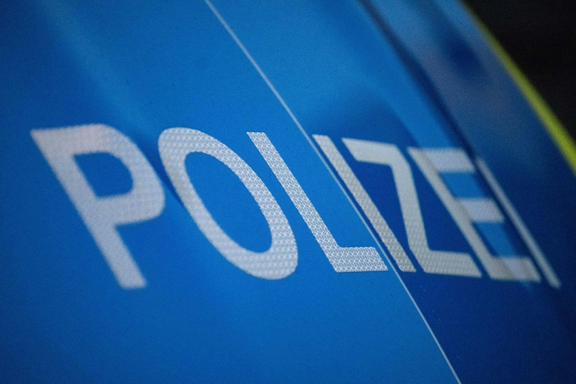 ILLUSTRATION - Das Wort Polizei ist auf der Karosserie eines Polizeifahrzeugs zu sehen.  