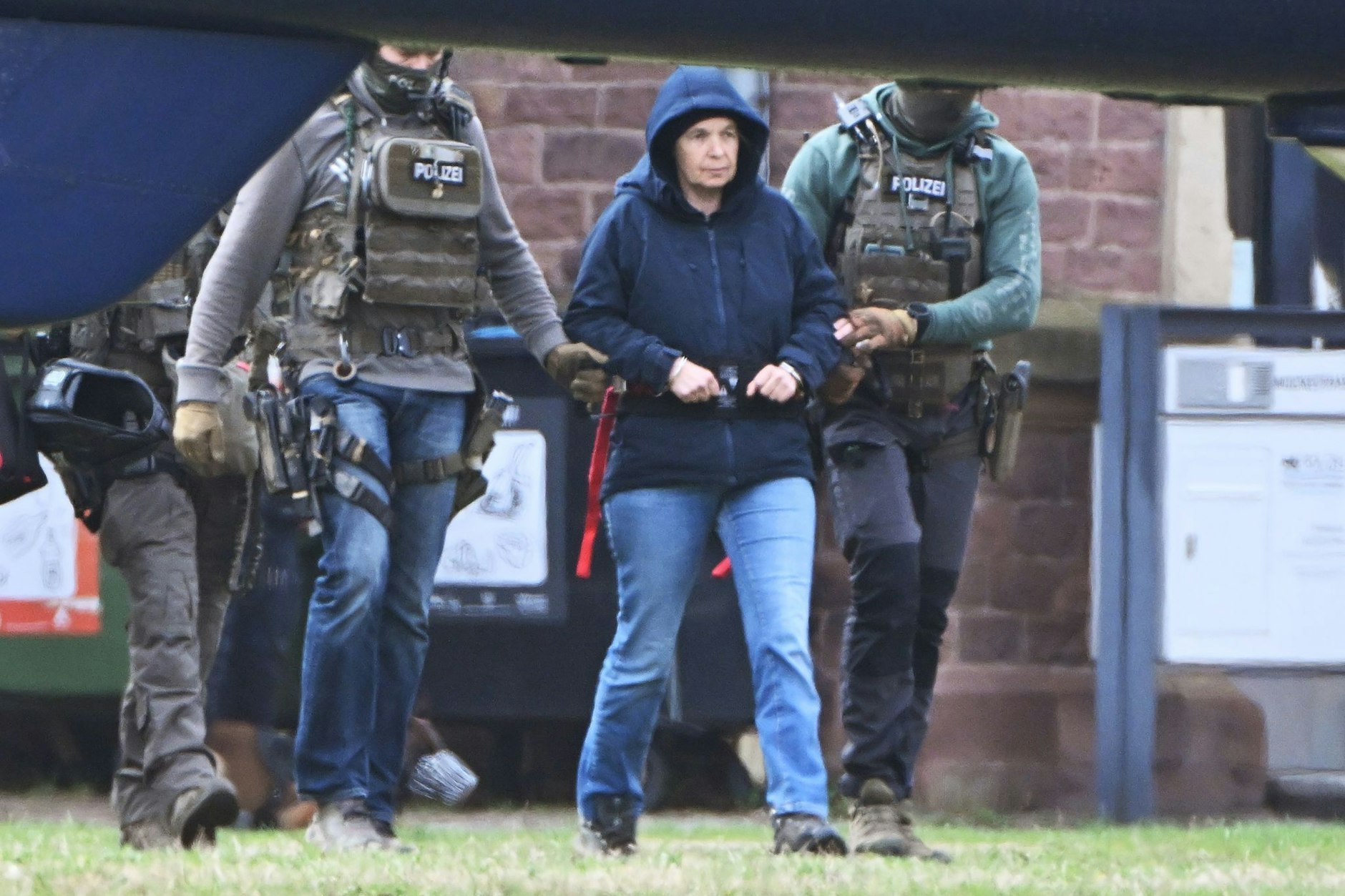 Im Innenhof eines Behördenzentrums wird die frühere RAF-Terroristin Daniela Klette zu einem Hubschrauber geführt.