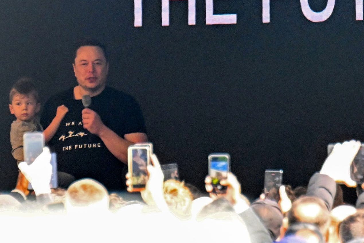 Tesla-Chef Elon Musk spricht in der Tesla-Gigafactory Berlin-Brandenburg zu den Mitarbeitern und hält dabei seinen Sohn auf dem Arm.