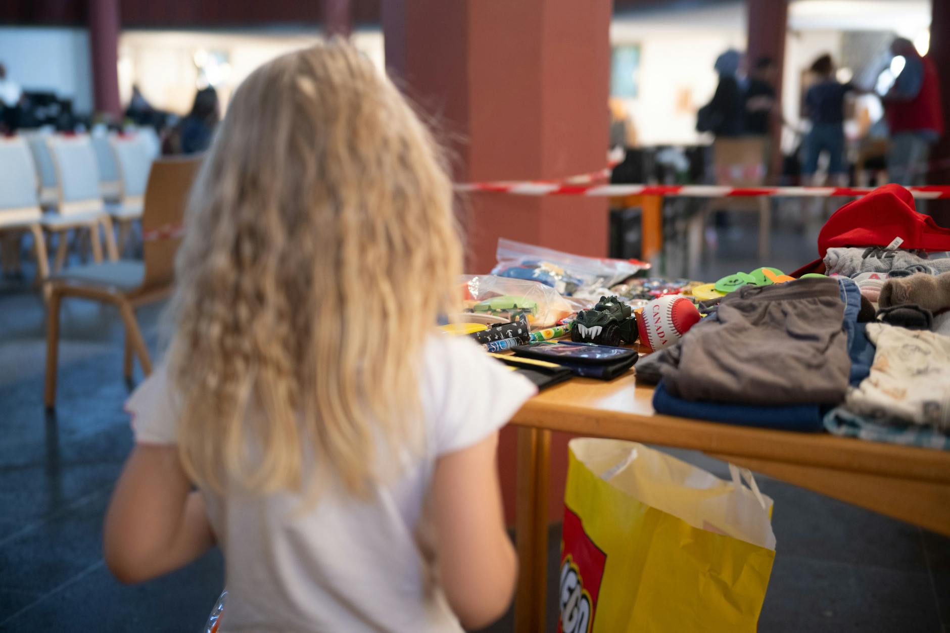Kinderarmut: Ein Mädchen steht in einer Ausgabestelle der Tafel an einem Tisch mit Spielzeug.