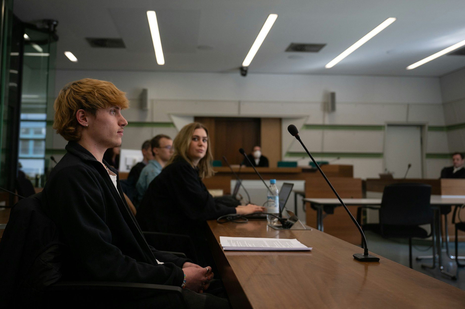 Der Angeklagte Maximilian H. (l.), eine Anwältin und der zweite Angeklagte (hinten) sitzen vor Beginn des Prozesses im Kriminalgericht Berlin-Moabit.