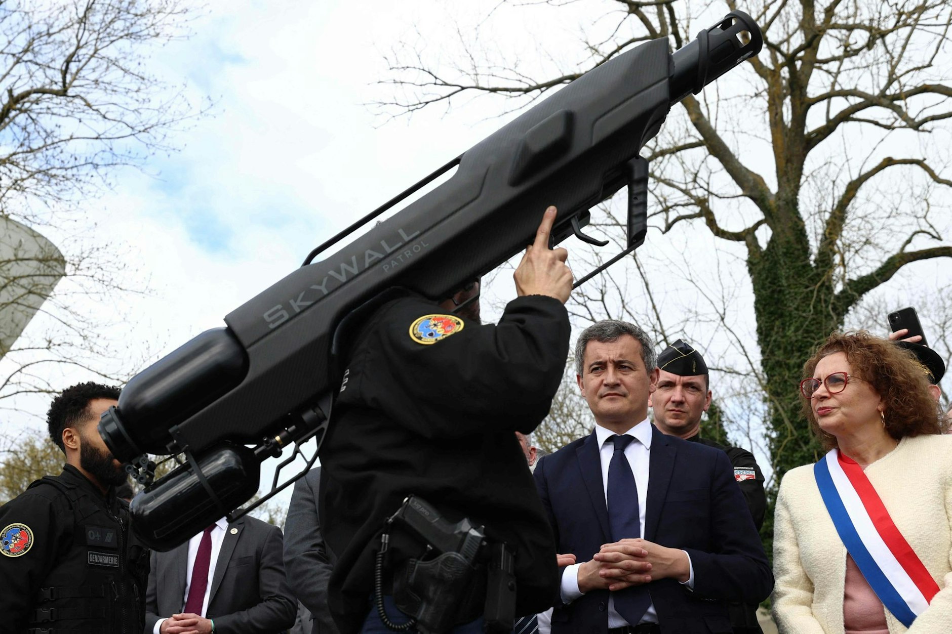 ARCHIV - Das etwas andere Kampfgerät: Dem französischen Innenminister Gerald Darmanin (M.) wird in Beynes eine Anti-Drohnen-Waffe vorgeführt.  