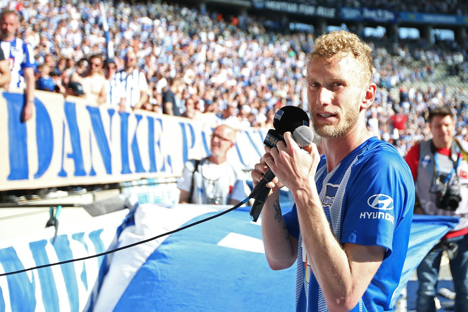 18. Mai 2019: Fabian Lustenberger steht nach seinem letzten Spiel für Hertha BSC mit zwei Mikrofonen in der Hand gerührt vor der Fankurve.