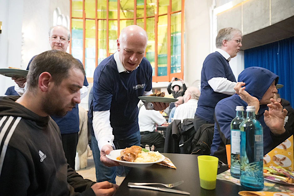 Kai Wegner (CDU, M), Regierender Bürgermeister von Berlin, serviert Essen während eines Osterbrunchs für Menschen ohne Wohnung.  