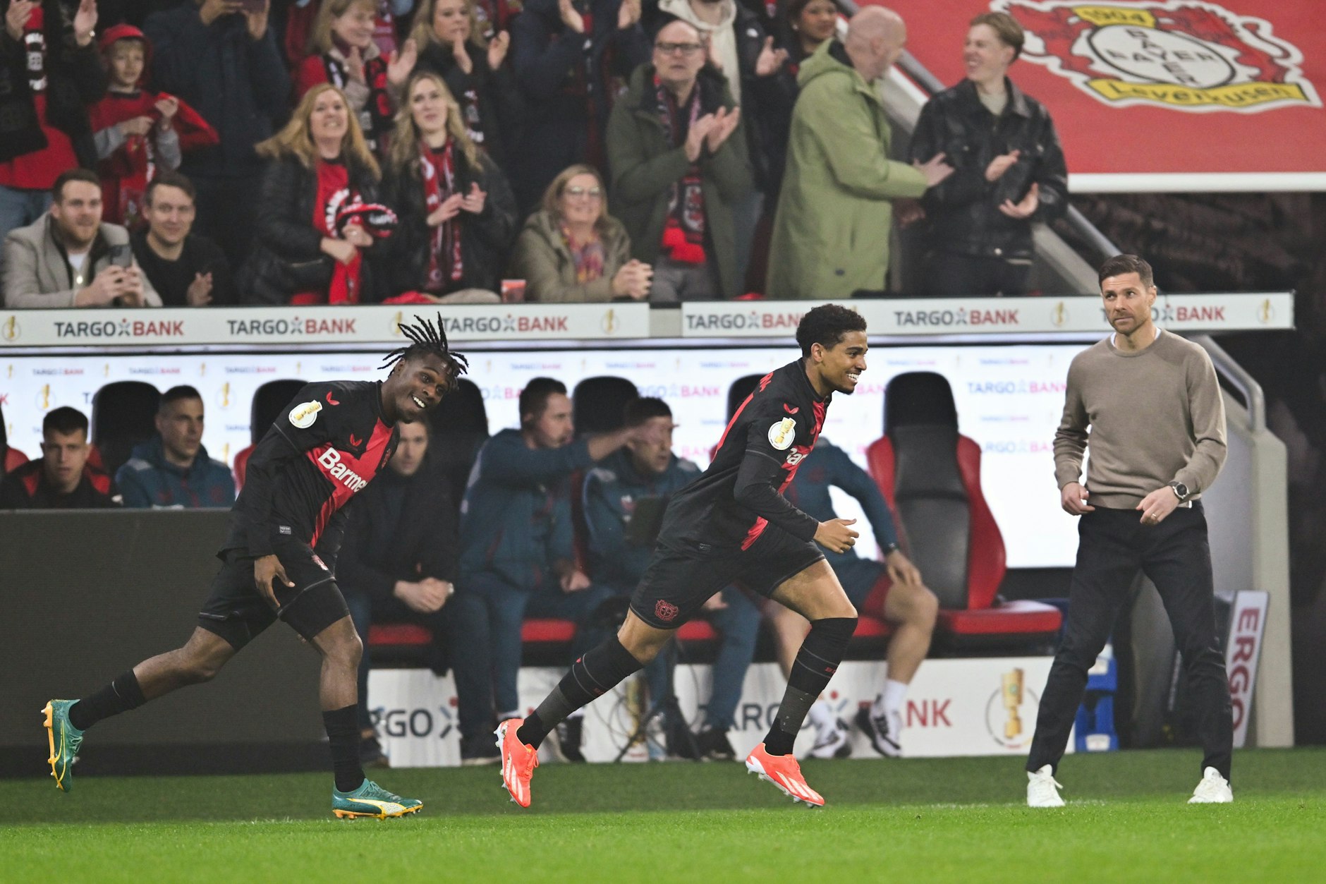 Fußball: DFB-Pokal, Bayer Leverkusen - Fortuna Düsseldorf. Leverkusens Jeremie Frimpong (l-r), Leverkusens Amine Adli und Leverkusens Trainer Xabi Alonso jubeln nach dem Tor zum 1:0. Am Ende steht es 4:0. 