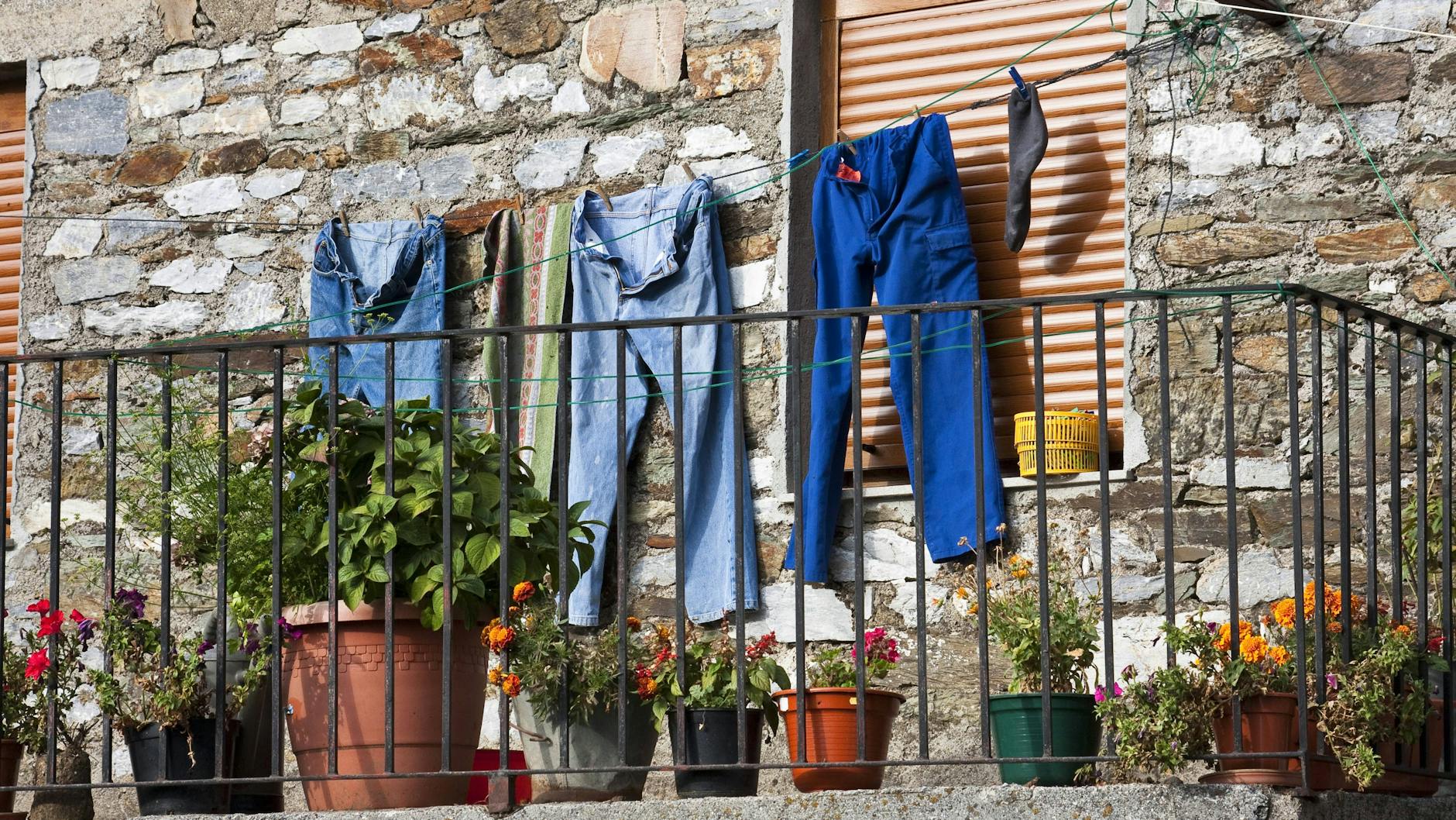 Eine Arbeitshose und Jeans trocknen auf einer Wäscheleine. Waschen sollte man sie besser „auf links“.