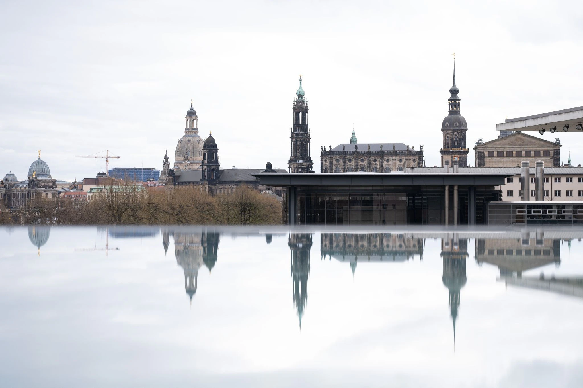 Die Kulisse der Dresdner Altstadt mit der Frauenkirche (l.) spiegelt sich in einer mit Regenwasser bedeckten Scheibe.  
