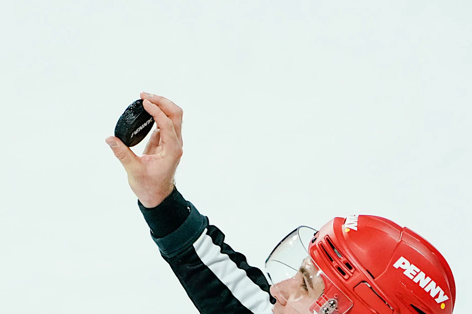 Ein Schiedsrichter hält den Puck in der Hand.  