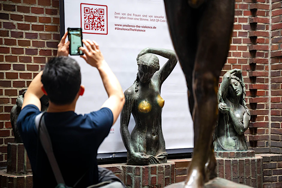 Bremen: Ein Plakat von „Terre de Femmes“ mit einem QR-Code hängt hinter der Bronzeskulptur „Jugend“ des Künstlers Bernhard Hoetger.&nbsp;