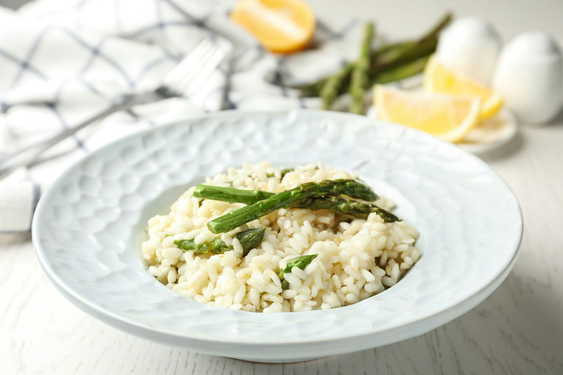 Cremiges Spargel-Risotto mit Parmesan auf einem Teller serviert, garniert mit frischen Kräutern. Zur Deko eignet sich auch gebratener grüner Spargel.