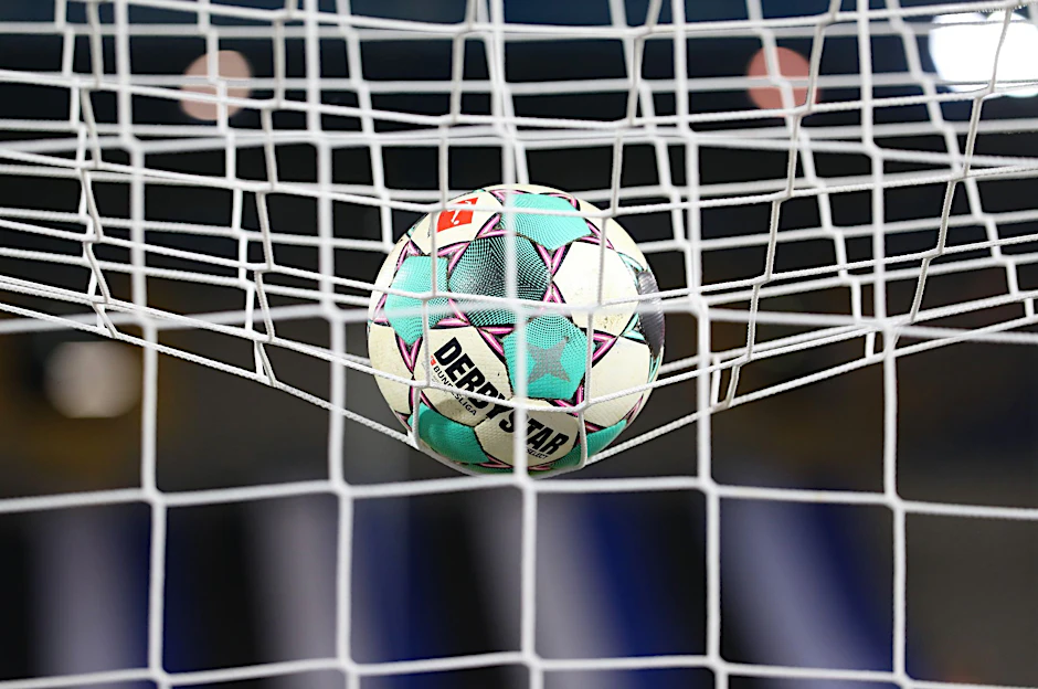 ARCHIV - Ein Fußball liegt vor der Partie im Netz.  