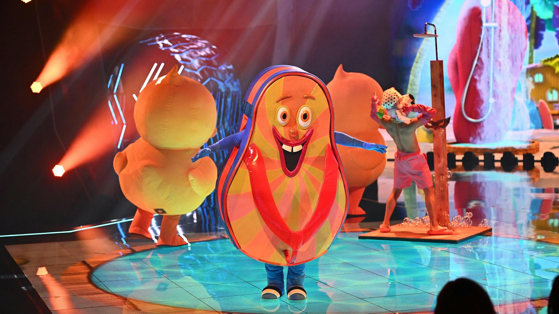 Der Flip Flop in der zweiten Ausgabe von Masked Singer. Die Kleidung unter dem Kostüm ist blau, ein anderes Gesicht zeigt nach vorn.