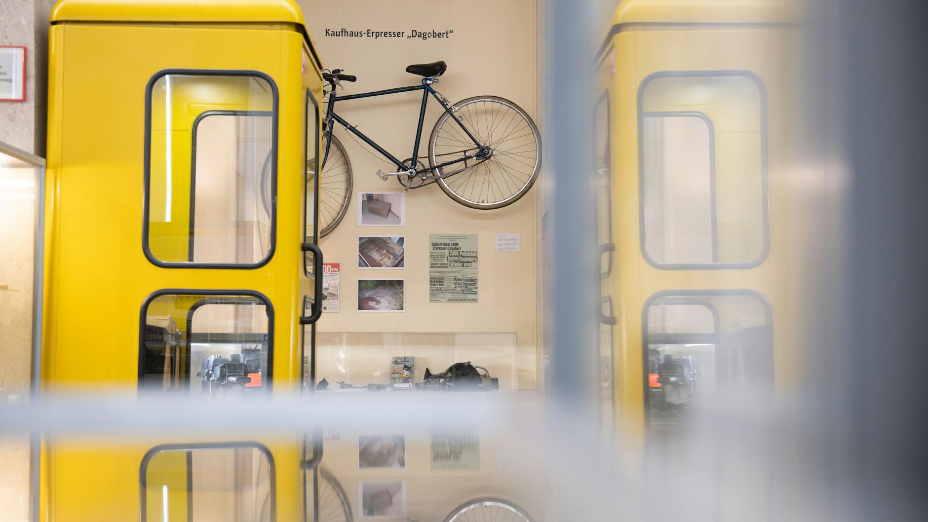 Eine Telefonzelle und Ausstellungsstücke wie das Fahrrad von Kaufhaus-Erpresser "Dagobert" sind in der Polizeihistorischen Sammlung der Polizei Berlin zu sehen.