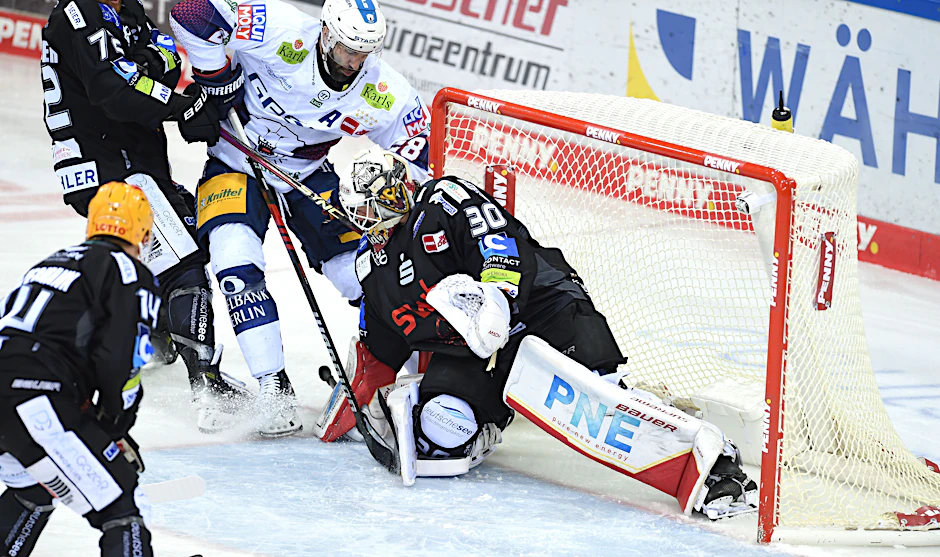 Berlins Patrice Cormier kämpft gegen Bremerhavens Torwart Kristers Gudlevskis (rechts) und Phillip Bruggisser um den Puck.