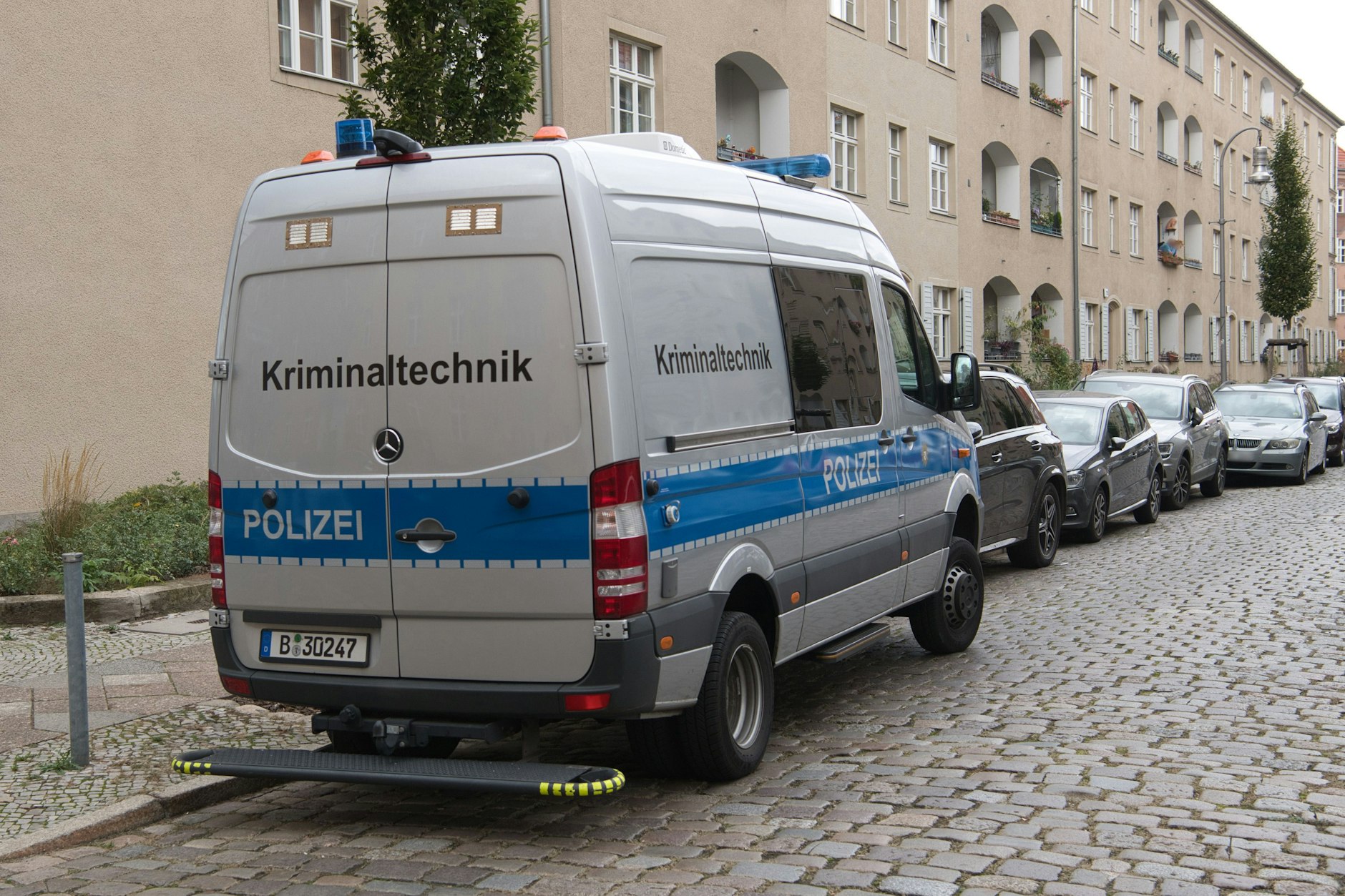 Ein Einsatzfahrzeug der Kriminaltechnik der Polizei steht vor einer Häuserzeile an der Kinzerallee in Köpenick. Dort wurden die Leichen einer Frau und eines Kindes in einer Wohnung gefunden.
