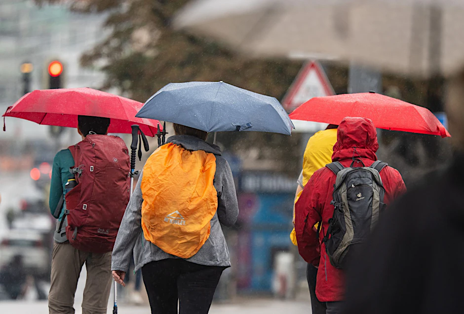 Menschen schützen sich bei Regen mit ihren Schirmen.  