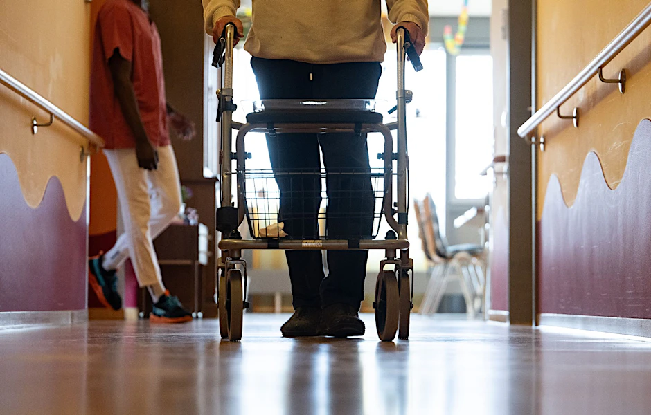 ARCHIV - Ein Bewohner eines Pflegeheims geht mit einem Rollator einen Gang entlang.  