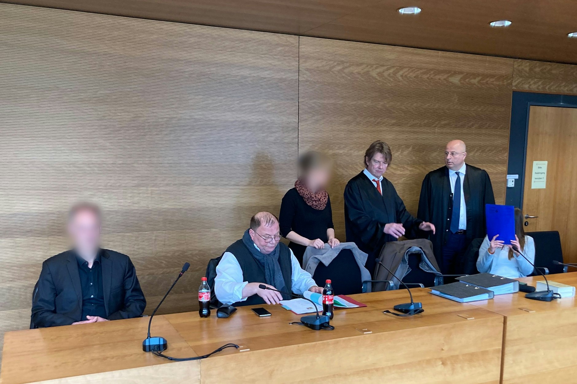 Die drei Angeklagten im Prozess wegen mutmaßlicher Beleidigung des Virologen Christian Drosten mit ihren Anwälten. Ein Paar wurde verurteilt, gegen eine weitere ursprüngliche Angeklagte war das Verfahren zuvor wegen Geringfügigkeit eingestellt worden