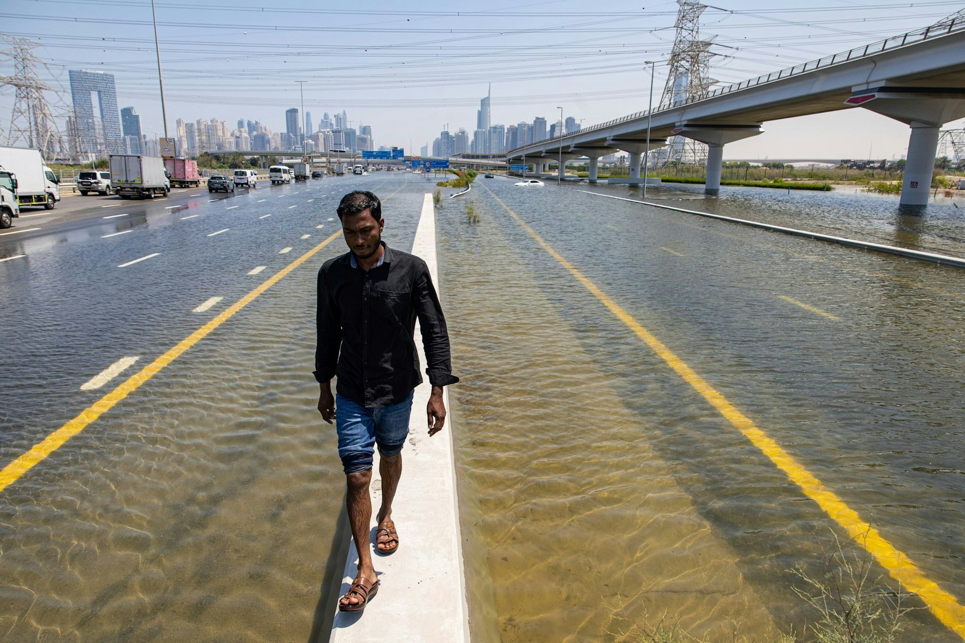 dpatopbilder - In den Vereinigten Arabischen Emiraten hat sich der heftigste Regen seit Jahrzehnten ereignet und Teile der Metropole Dubai überschwemmt. Ein Mann geht entlang einer Straßensperre auf der Sheikh Zayed Road.