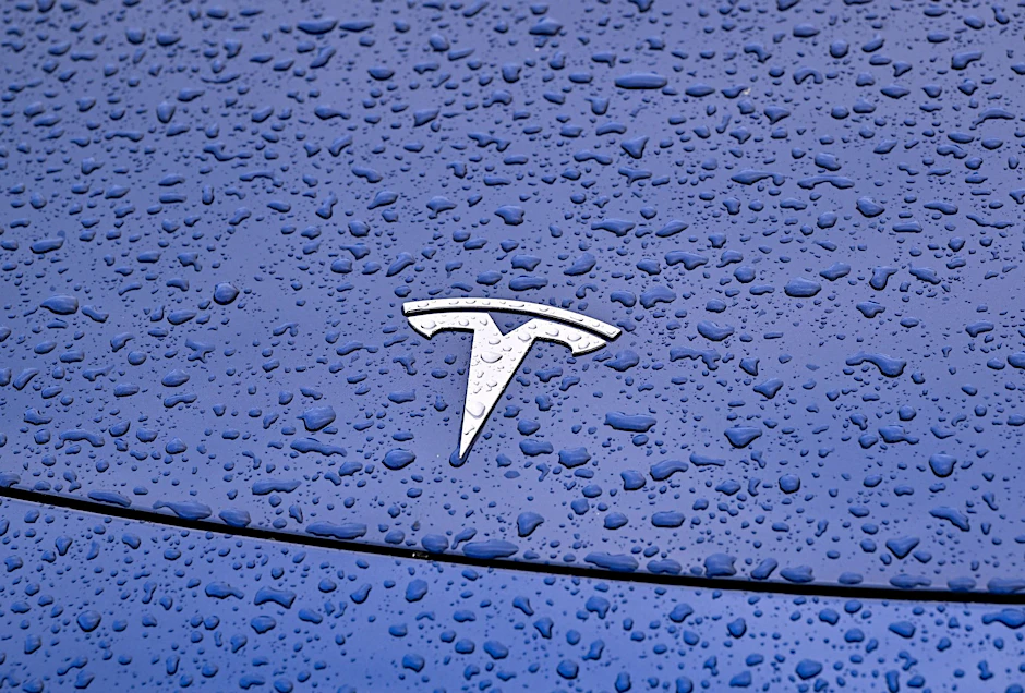 ARCHIV - Steht Tesla im Regen? Der US-Hersteller will mehr als zehn Prozent seiner Stellen weltweit abbauen.  