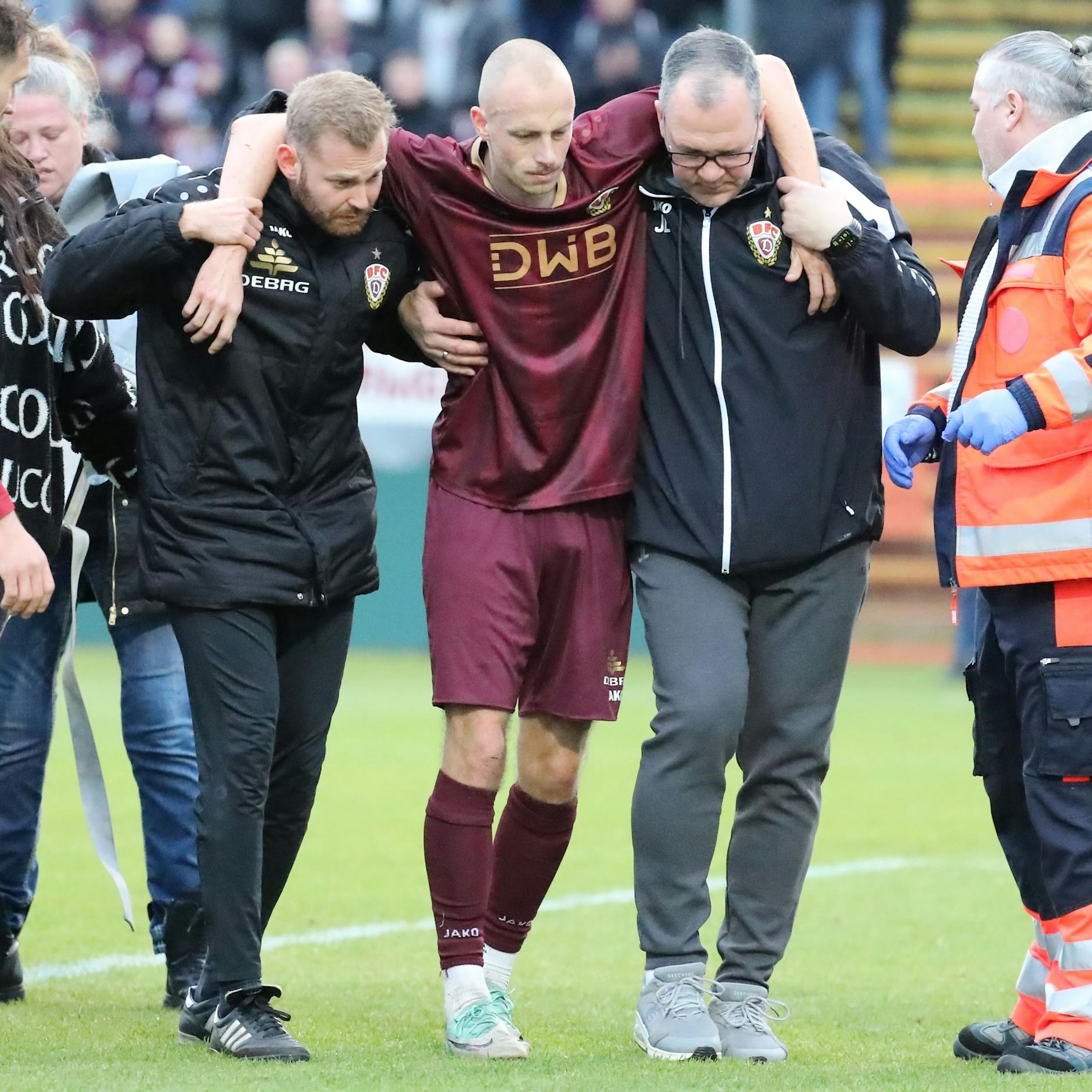 Steffen Eder verlässt - gestützt von Dynamo-Physio Nils Vielrose (l.) und Teammanager Jörn Lenz (r.) - den Rasen im Sportforum. 