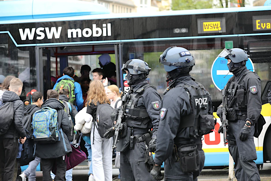dpatopbilder - Polizisten führen Schüler in Wuppertal aus dem Gebäude in einen Evakuierungsbus.  
