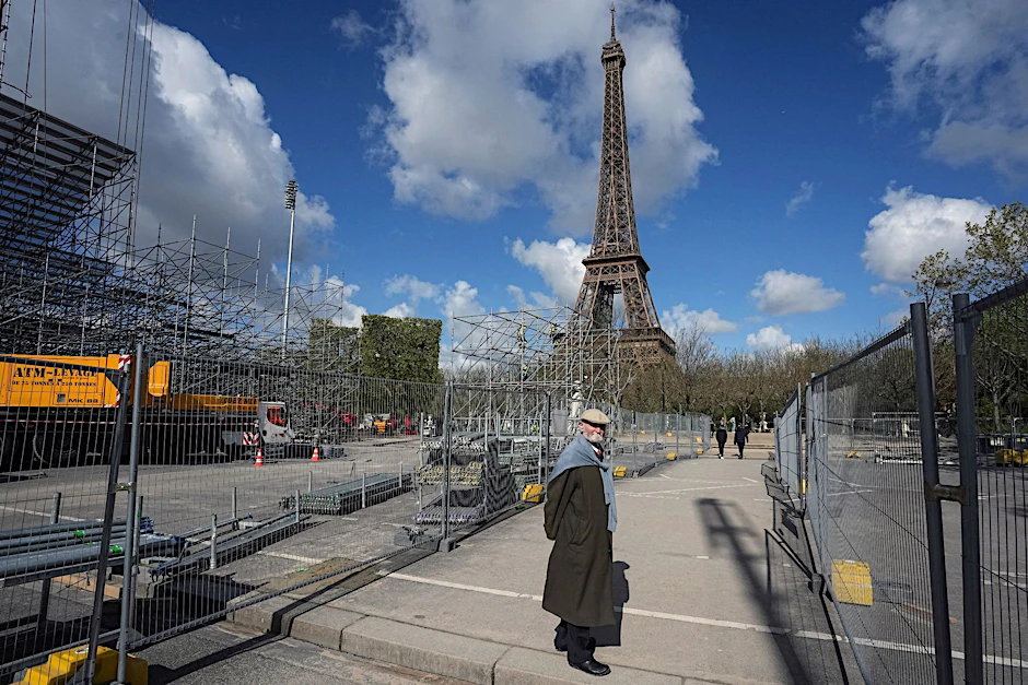 Ein Mann geht an einer Baustelle auf dem Champ-de-Mars in der Nähe des Eiffelturms im Vorfeld der Olympischen Spiele 2024 in Paris vorbei.  