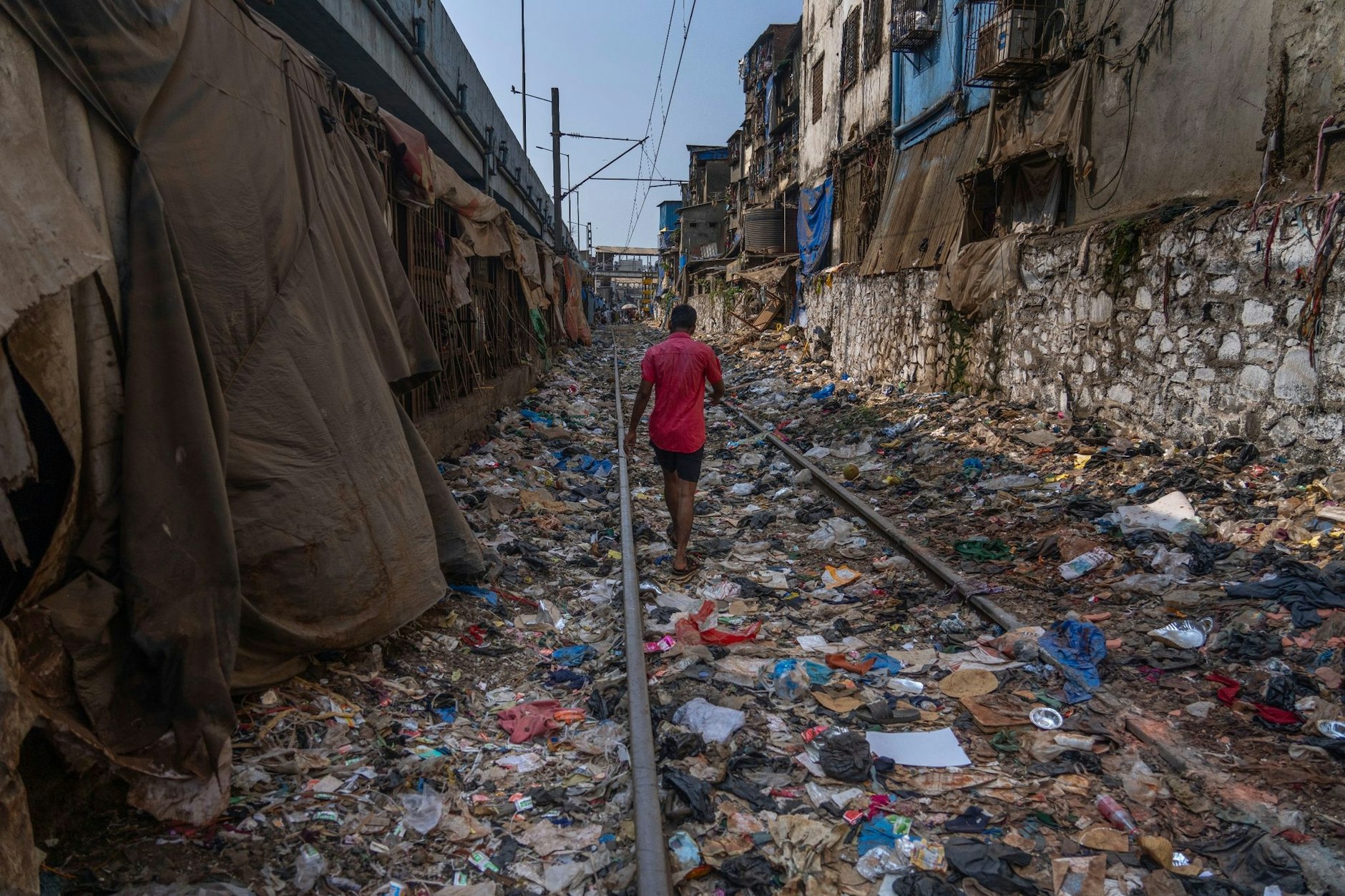 Ein Mann geht am Tag der Erde über ein mit Plastik und anderen Abfällen übersätes Bahngleis in Mumbai.