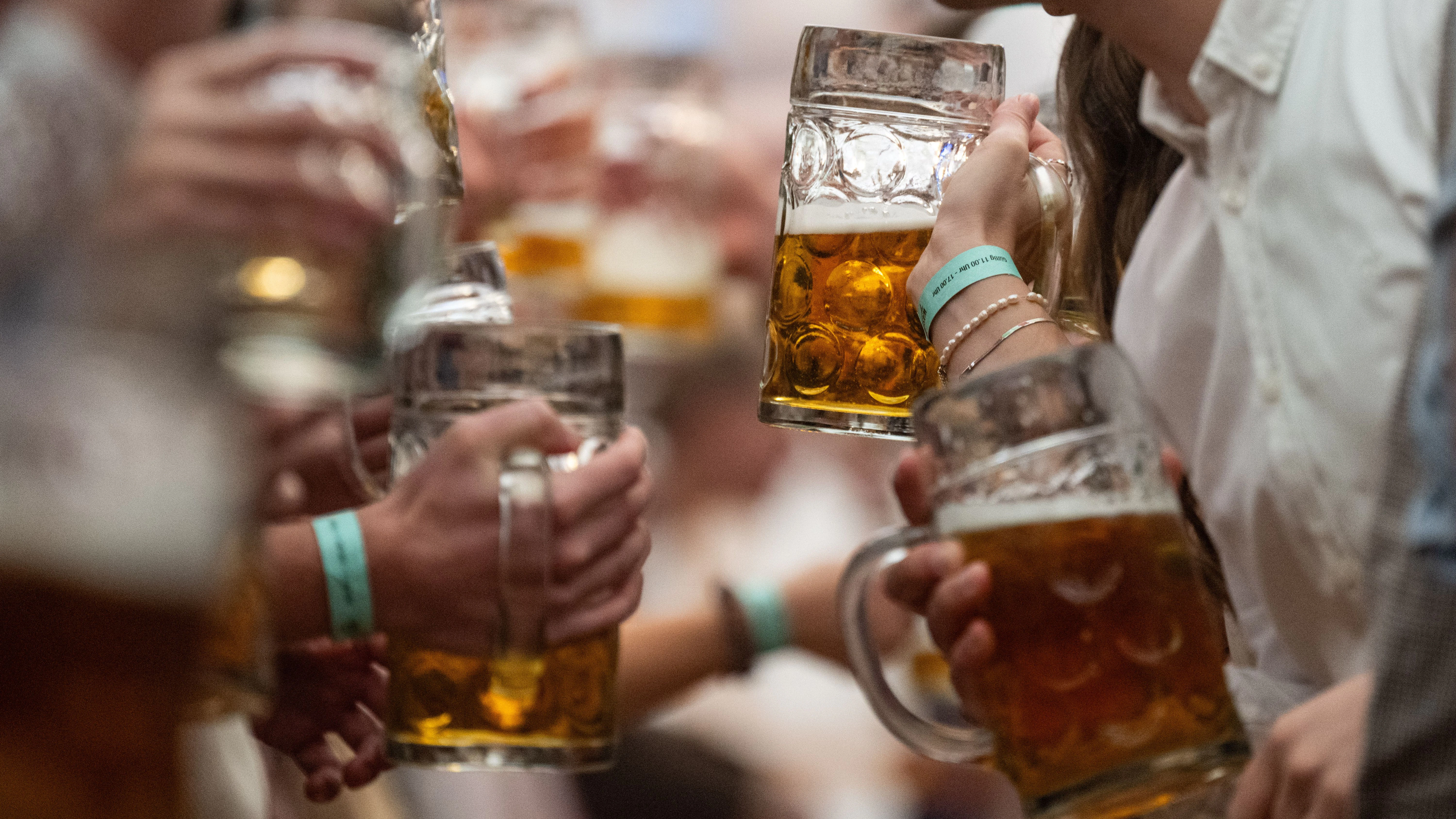 Hohe Ansteckungsgefahr: Besucher haben in einem Festzelt des Stuttgarter Frühlingsfestes Bierkrüge in den Händen. 