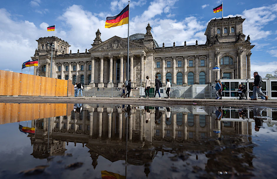 Passanten gehen beim sonnigen Wetter an dem Reichstagsgebäude vorbei.