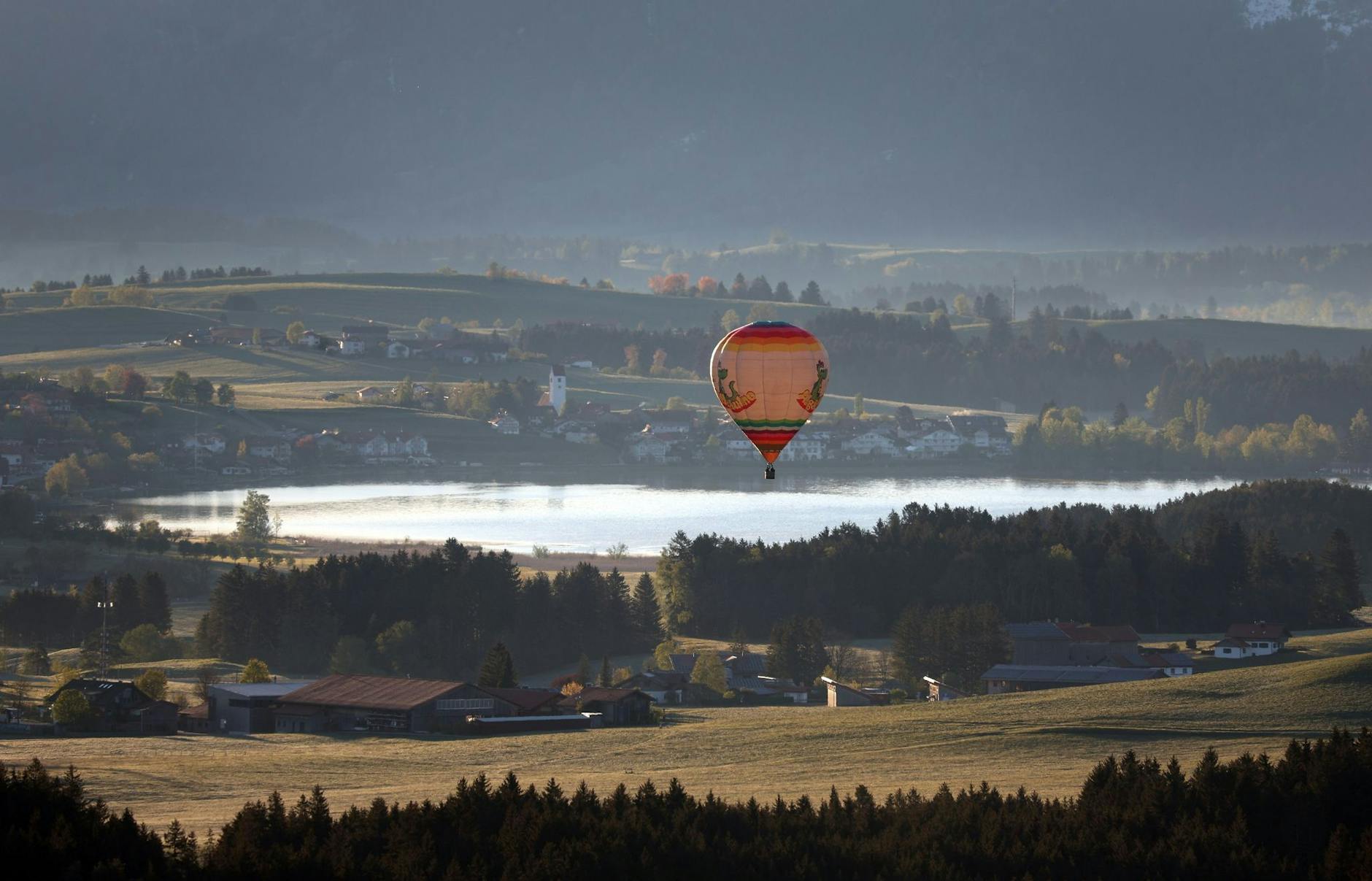 Ein Heißluftballon gleitet über den Hopfensee im Allgäu.