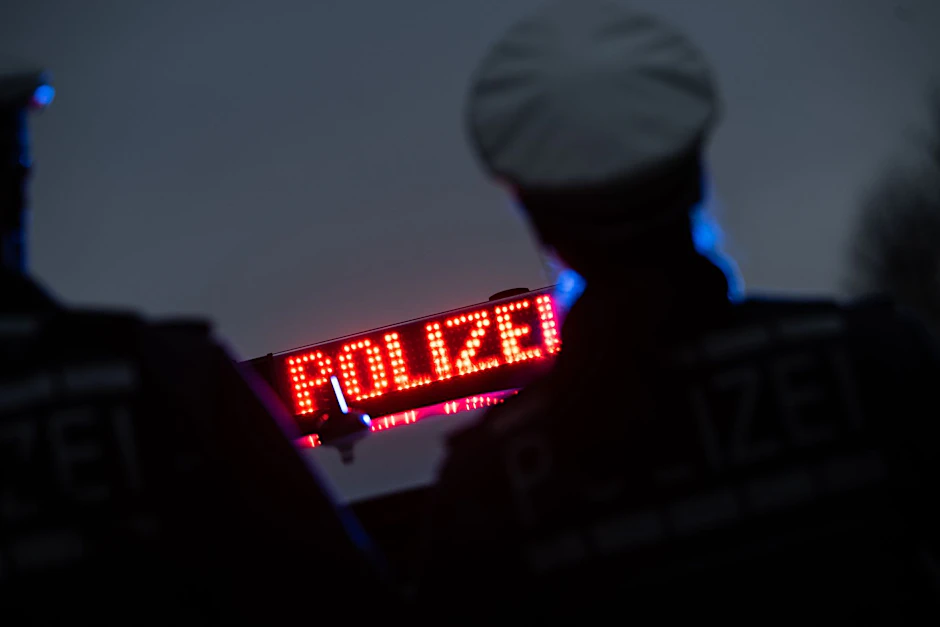 ILLUSTRATION - Zwei Polizisten stehen im Rahmen eines Fototermins vor einem Polizeifahrzeug.  