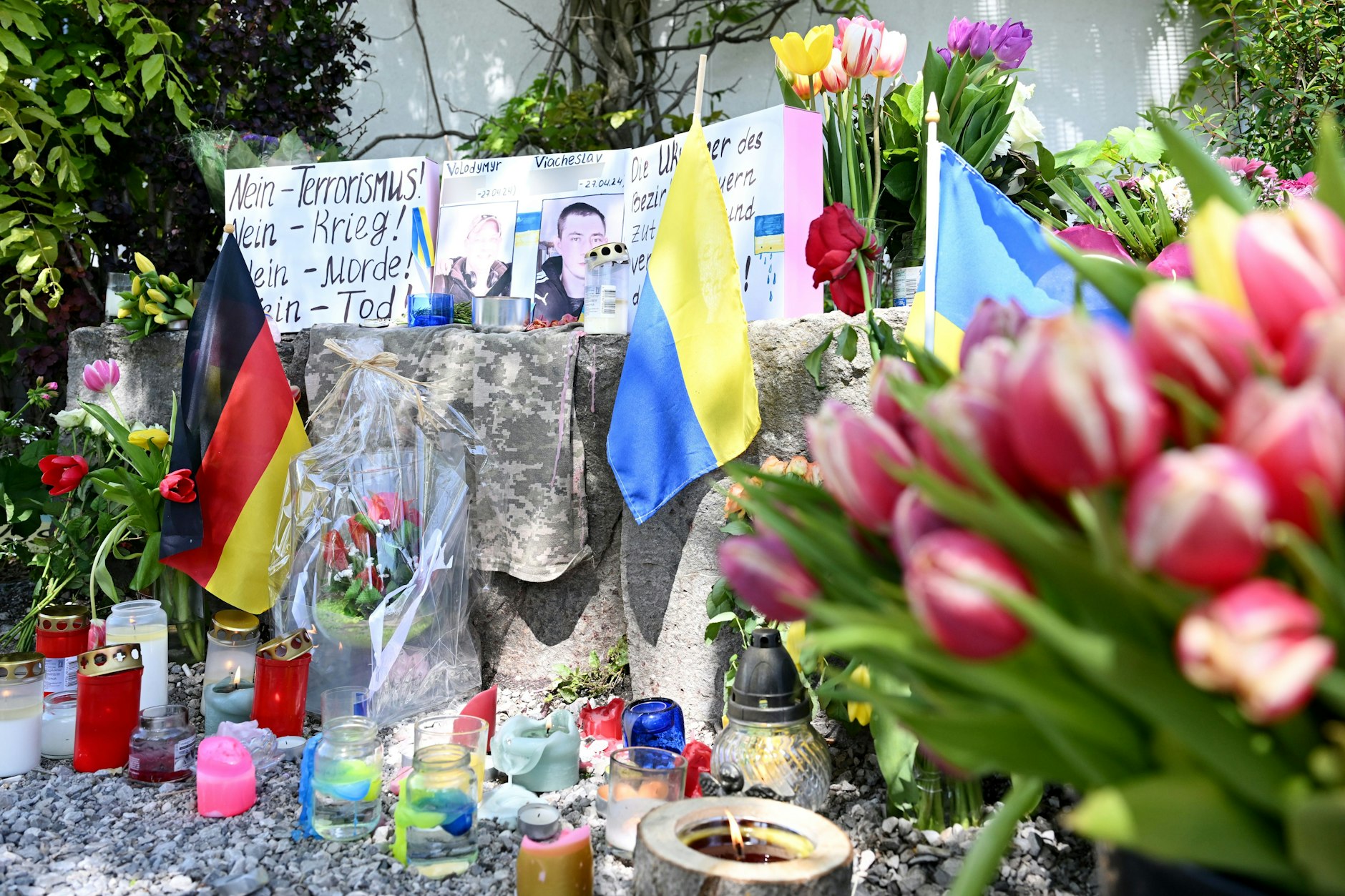 Neben einem Einkaufszentrum, an dem am Samstag zwei Männer aus der Ukraine getötet worden sind, haben Menschen Blumen und Plakate niedergelegt.