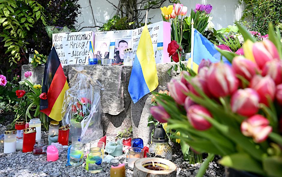Neben einem Einkaufszentrum, an dem am Samstag zwei Männer aus der Ukraine getötet worden sind, haben Menschen Blumen und Plakate niedergelegt.