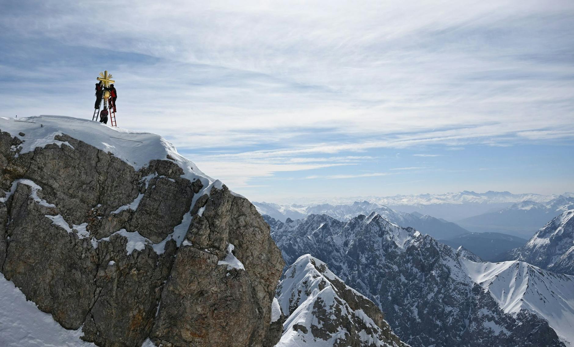 Die im Tal restaurierten Strahlen des Gipfelkreuzes der Zugspitze werden von Mitarbeitern wieder angebracht.