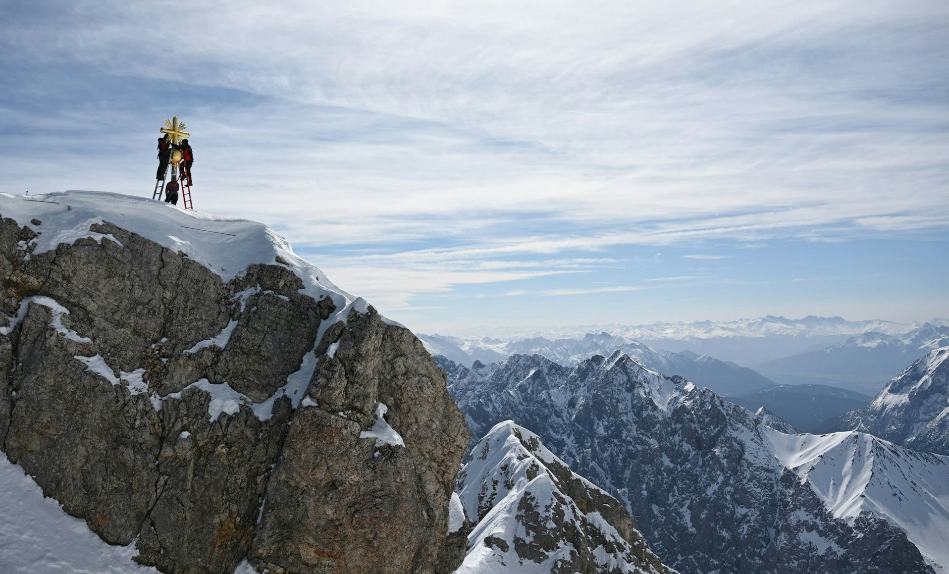 Die im Tal restaurierten Strahlen des Gipfelkreuzes der Zugspitze werden von Mitarbeitern wieder angebracht.  