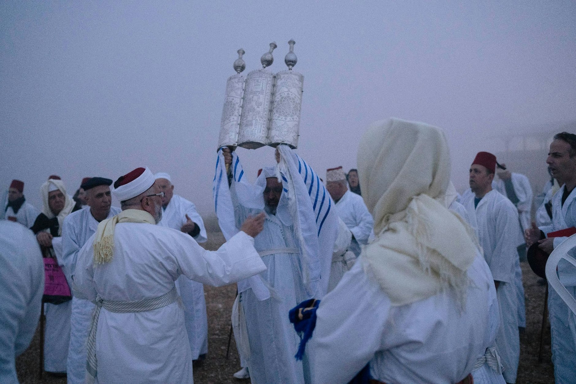 Ein Mitglied der samaritanischen Religionsgemeinschaft hält eine Tora-Schriftrolle hoch. Gäubige beten während der Pessach-Wallfahrt am Berg Garizim in Nablus.  