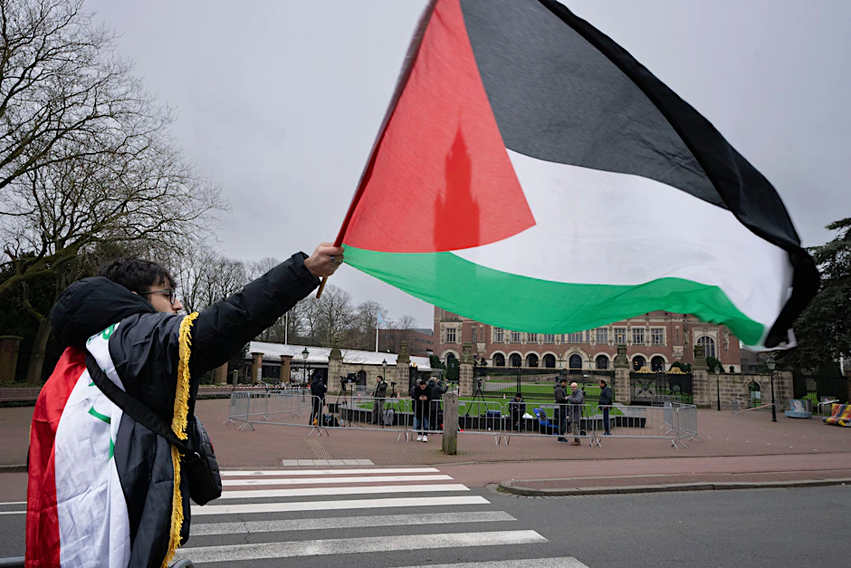 ARCHIV: 21.02.2024, Niederlande, Den Haag: Ein Mann schwenkt eine palästinensische Fahne und demonstriert vor dem Obersten Gerichtshof der Vereinten Nationen.